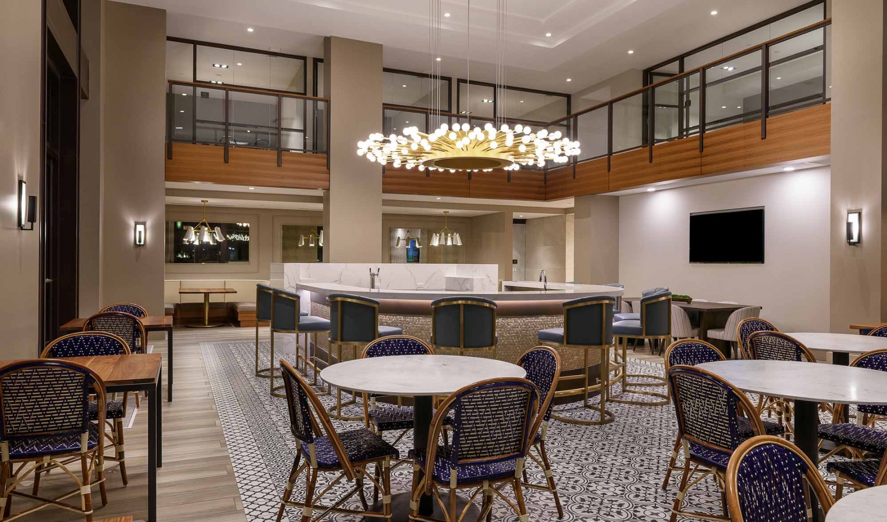Indoor community dining area with large chandelier and dining tables with blue chairs 